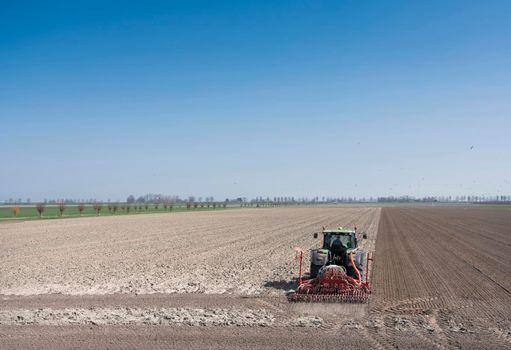 wissenkerke, netherlands, 31 march 2021: farmer works his land on rural countryside of noord beveland in dutch province zeeland on sunny spring day under blue sky in the netherlands