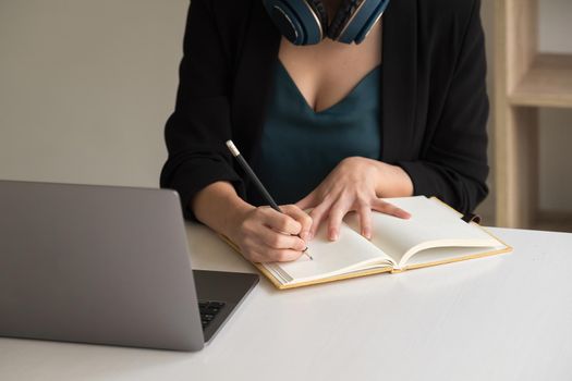 Woman make notes sit at work desk while study online watching webinar podcast on laptop listening learning education course conference, elearning concept