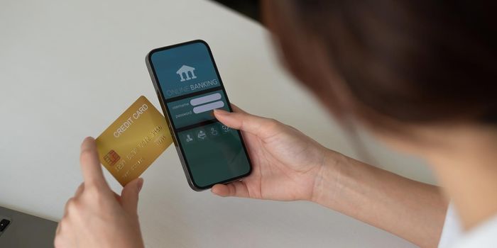 Close up hand of woman making card payment through mobile phone to pay bills.