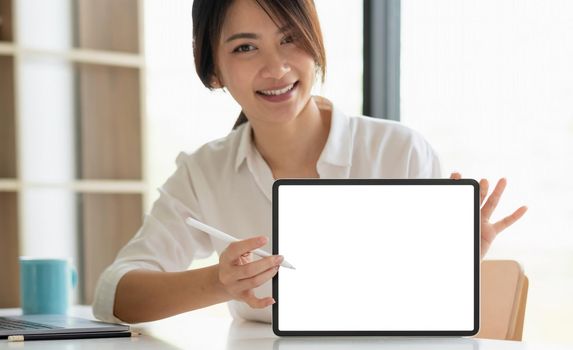 Smiling beautiful asian businesswoman showing blank tablet pc monitor, with copyspace area for slogan or text message
