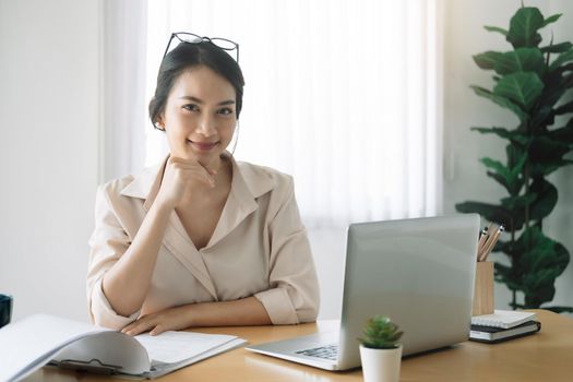 Portrait of businesswoman with laptop while checklist on a document at her office