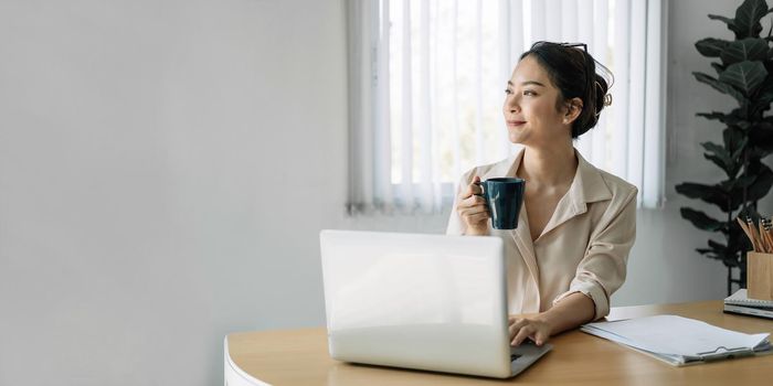 Young asian businesswoman beautiful charming smiling holds cup in the office.