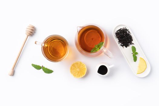 Design concept top view of honey black tea with yellow lemon and mint leaf on white table background.