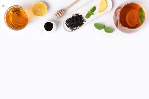 Design concept top view of honey black tea with yellow lemon and mint leaf on white table background.
