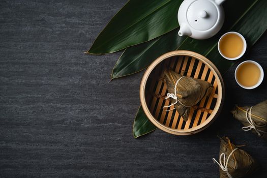 Zongzi rice dumpling top view for Chinese traditional Dragon Boat Festival (Duanwu Festival) over dark black slate background.