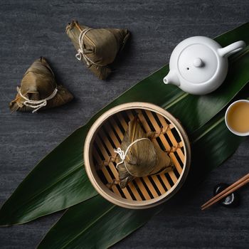 Zongzi rice dumpling top view for Chinese traditional Dragon Boat Festival (Duanwu Festival) over dark black slate background.