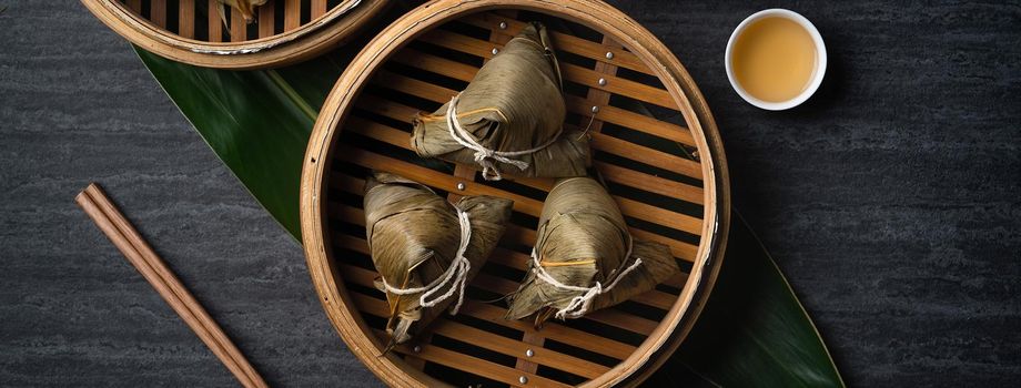 Zongzi rice dumpling top view for Chinese traditional Dragon Boat Festival (Duanwu Festival) over dark black slate background.