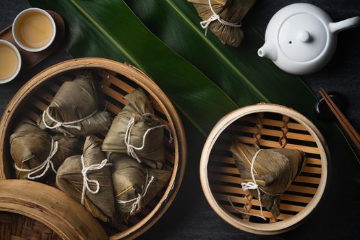 Zongzi rice dumpling top view for Chinese traditional Dragon Boat Festival (Duanwu Festival) over dark black slate background.