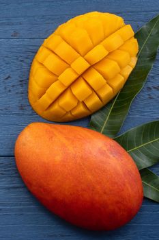 Top view design concept of beautiful mango tropical fruit with sliced chuncks over blue table background.