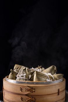 Zongzi rice dumpling for Chinese traditional Dragon Boat Festival (Duanwu Festival) over dark background.