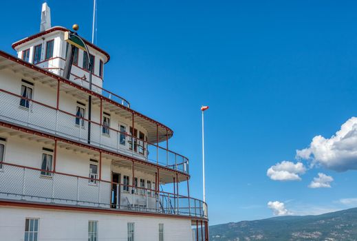 Upper decks of old steam vessel on blue sky background.