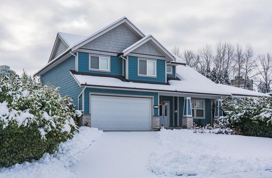 Family house with front yard in snow. Residential house on winter cloudy day
