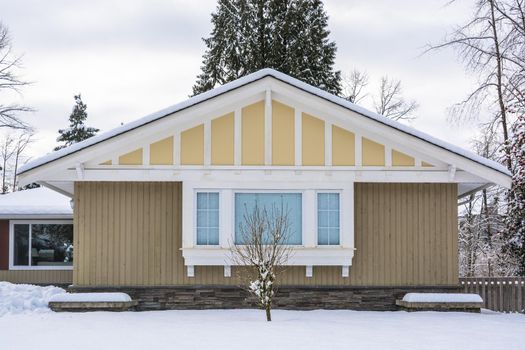 Side of Family house with front yard in snow. Residential house on winter cloudy day