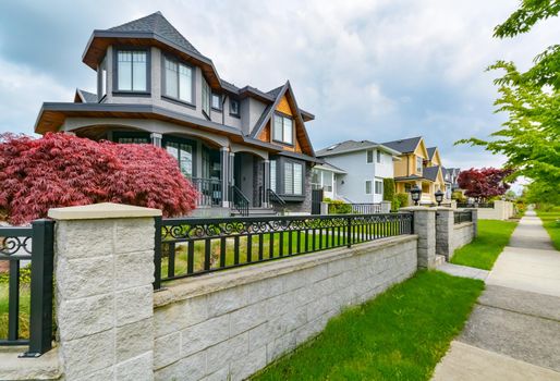 Residential houses with concrete pathway along the front yard. Metal fence in front of residential house