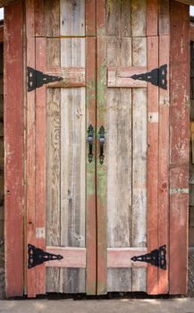 Wooden doors of plank house with black metal handles and hinges