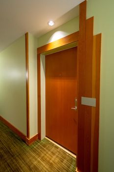 Wooden entrance door of residential apartment with light source above