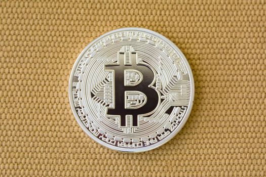 Obverse of metal bitcoin on yellow fiber background. Crypto currency coin