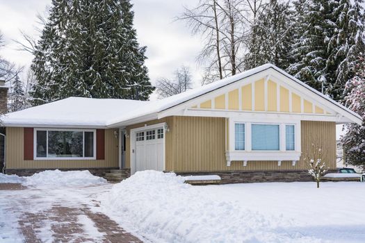 Family house with front yard in snow. Residential house on winter cloudy day