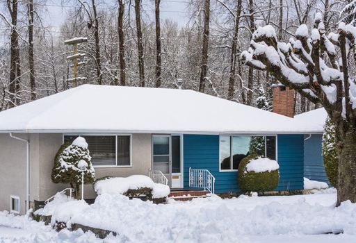 Family house with front yard in snow. Residential house on winter cloudy day