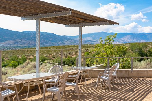 Recreational area with chairs and tables in shadow of the canopy with mounain view background