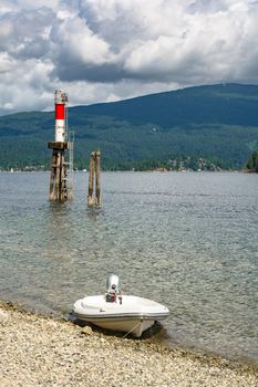 Motorized boat moored at stone shore with ship channel light behind