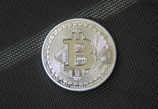 Obverse of metal bitcoin on black fiber background. Crypto currency coin