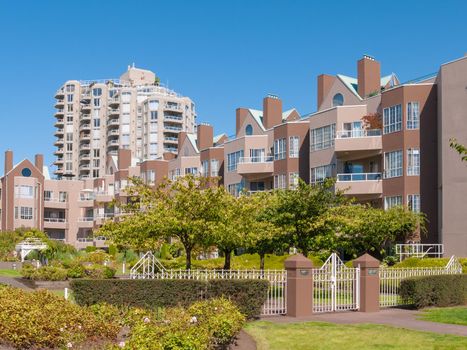 Gated residential complex with recreational area in front. Cityscape on blue sky background