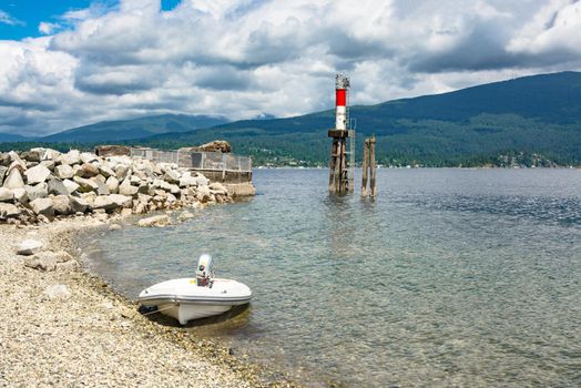 Motorized boat moored at stone shore with ship channel light behind