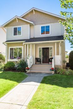 Main entrance of residential house with concrete pathway over the front yard on bright sunny day