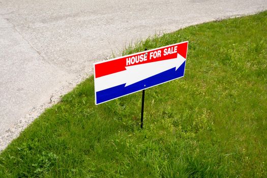 'House for sale' open house directional pointer on green lawn at road turn