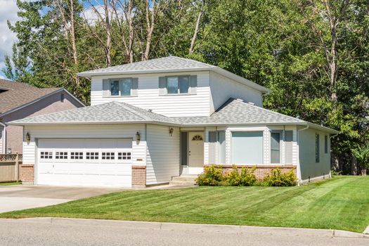 A perfect neighbourhood. Family house with landscaped front yard on sunny day in British Columbia