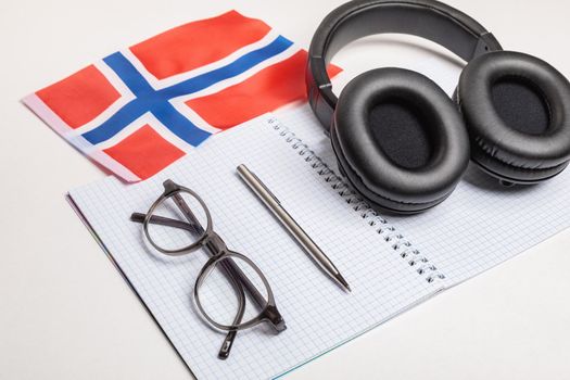 Learning foreign languages in Norway with audio recordings and headphones. Notepad, glasses, pen.