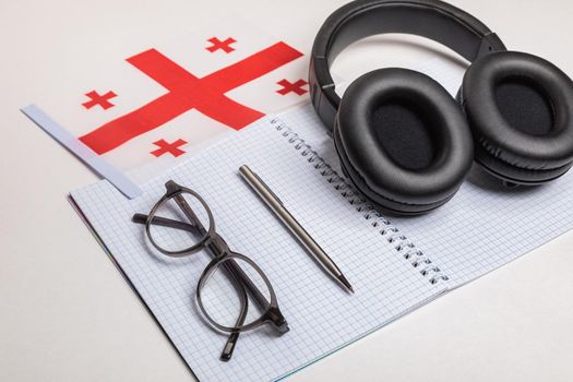 Learning foreign languages in Georgia using audio recordings and headphones. Notepad, glasses, pen.