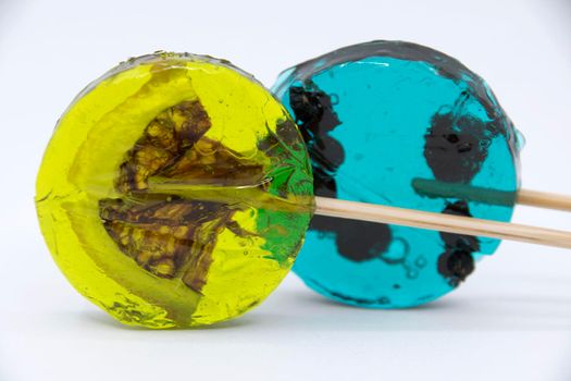 Lollipop with black currant inside turquoise color and lollipop with yellow lemon slice on a white background.