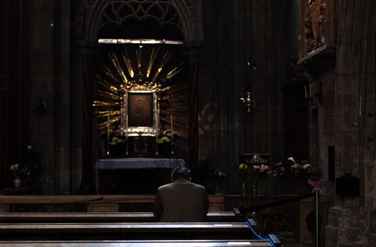 Wien - April 3, 2021: man praying on a pew in a church.