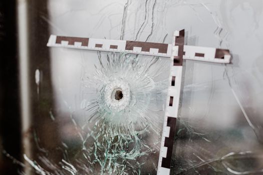 bullet holes in a glass shop window marked with a police tape.