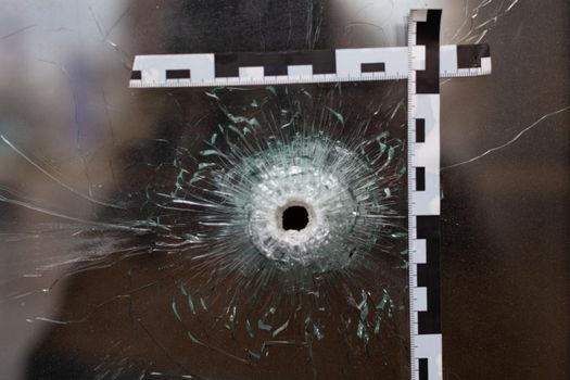 bullet holes in a glass shop window marked with a police tape.