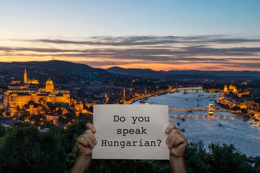 a man holding a sign with a panoramic view of Budapest in the background