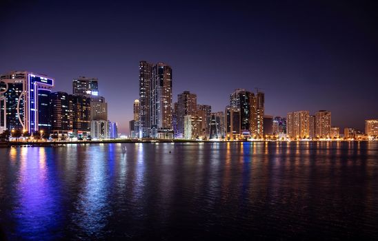 Sharjah,UAE - Dec 2nd 2020. Panoramic view of the illuminated sky scrappers showing beautiful reflections in water captured at the Al Majaz waterfront Sharjah , UAE.