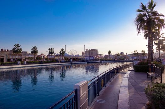 DUBAI, UAE - DEC-16 2020 Beautiful view of the country pavilions ,and Canal with pleasure boats in the park entertainment center captured in the evening sunset time at The Global Village , Dubai,UAE.