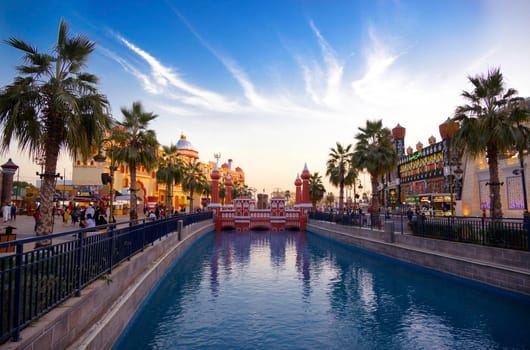 DUBAI, UAE - DEC-16 2020 Beautiful view of the country pavilions ,and Canal with pleasure boats in the park entertainment center captured in the evening sunset time at The Global Village , Dubai,UAE.