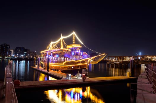 DEC 17, 2020, DUBAI ,UAE. Beautifully illuminated Dhow cruise dinner ship showing reflections on water captured at the Al seef village , Dubai, UAE.