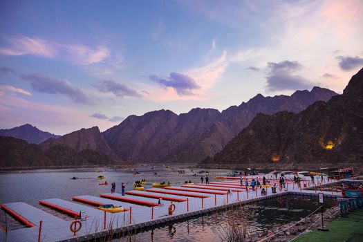 BEAUTIFUL AERIAL VIEW OF THE PADDLE BOATS, KAYAKS PARKED IN THE HATTA WATER DAM ON A CLOUDY DAY AT SUNSET TIME IN THE MOUNTAINS ENCLAVE REGION OF DUBAI, UNITED A
