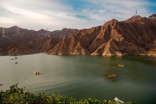BEAUTIFUL AERIAL VIEW OF BOATS, KAYAKS IN THE RAFIS WATER DAM AT SUNSET TIME IN THE MOUNTAINS ENCLAVE REGION OF KHOR FAKKAN, SHARJAH UNITED ARAB EMIRATES