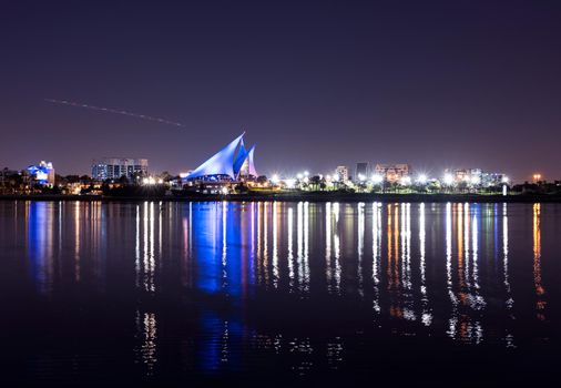 DEC 29TH 2020 ,DUBAI,UAE. Panoramic view of the distinctively sail-shaped illuminated clubhouse of Dubai Creek Golf and Yacht Club from across the Dubai Creek park, Deira Dubai UAE