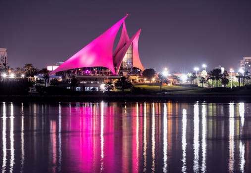 DEC 29TH 2020 ,DUBAI,UAE. Panoramic view of the distinctively sail-shaped illuminated clubhouse of Dubai Creek Golf and Yacht Club from across the Dubai Creek park, Deira Dubai UAE