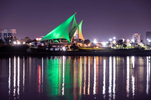 DEC 29TH 2020 ,DUBAI,UAE. Panoramic view of the distinctively sail-shaped illuminated clubhouse of Dubai Creek Golf and Yacht Club from across the Dubai Creek park, Deira Dubai UAE