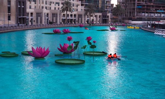 JAN 7th 2021, DUBAI, UAE. TOURISTS RIDING THE BOATS IN THE BEAUTIFUL LOTUS FLOWER POOL AT THE RECREATIONAL BOULEVARD AREA OF THE BURJ PARK, DUBAI,UAE.