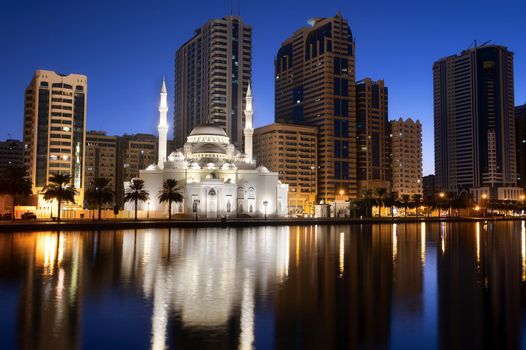 View of the beautifully illuminated Al Noor mosque during the early sunrise hours showing reflections in water captured from the Al Noor island Sharjah, UAE.