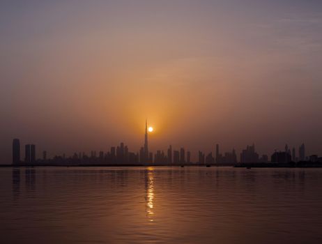 Panoramic view of the Dubai skyline with Burj khalifa and other sky scrapers forming silhouette captured at the sunset time at the Dubai creek, ras al khor, UAE.